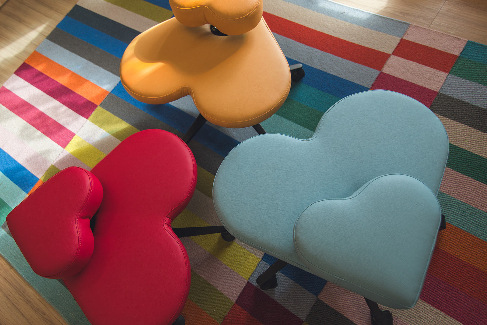 Three Fidget Seats for kids in tropical punch, cotton candy, and butterscotch colors on a multicolored rug