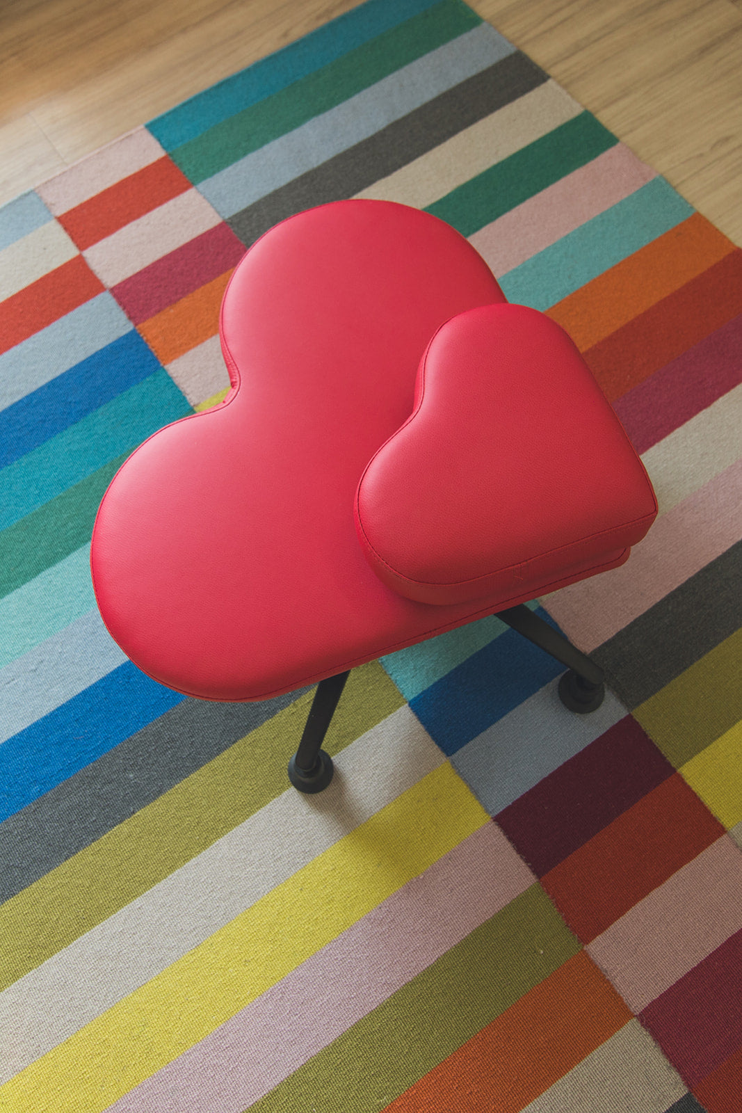 Red heart-shaped fidget chair on a colorful checkered rug